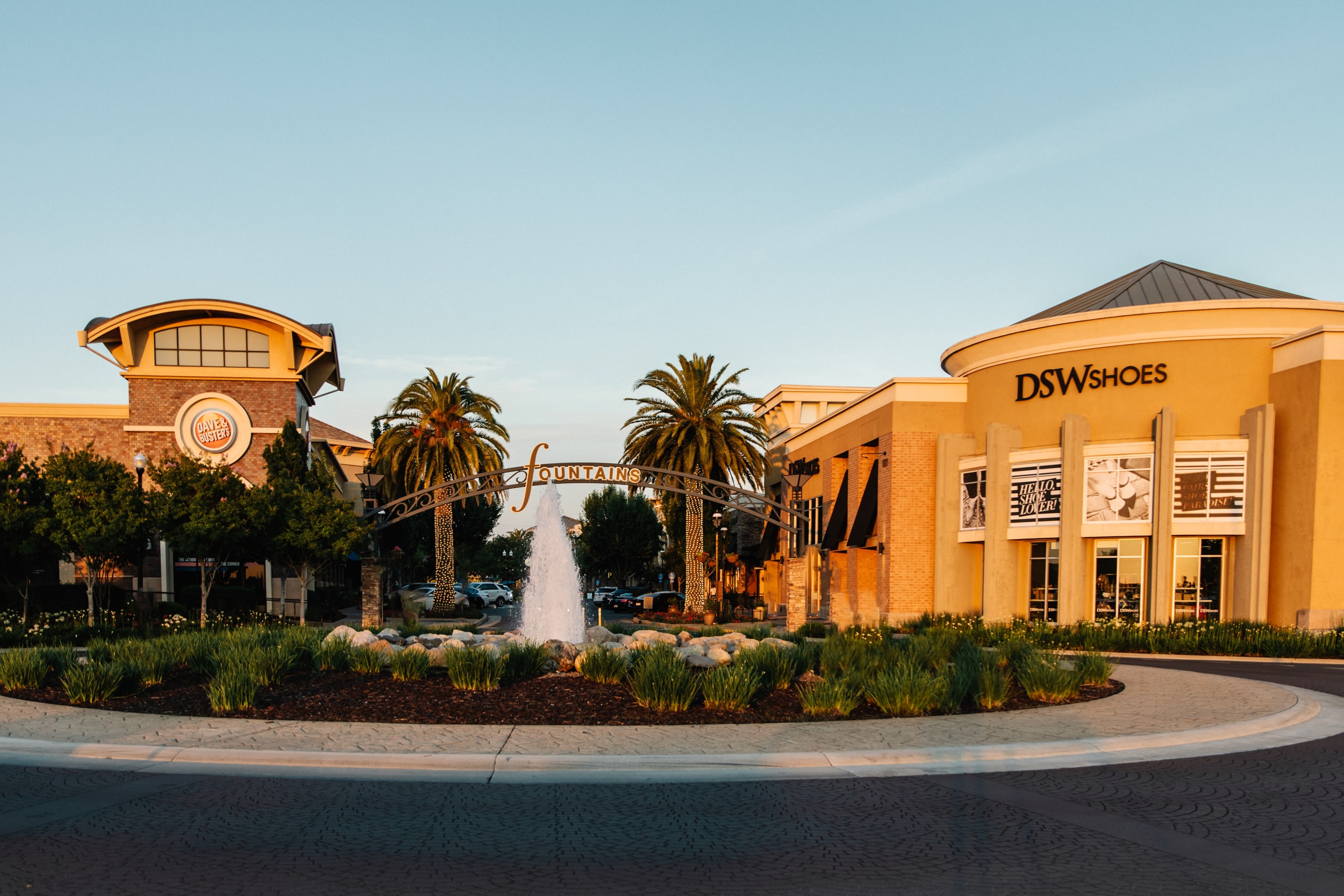 Photo of the Fountains at Roseville main roundabout, showing the main fountain, along with the Fountains at Roseville signage, DSW Shoes, and Dave & Buster.